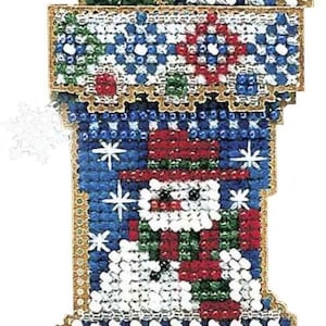 May include: A Christmas stocking ornament with a snowman design. The stocking is decorated with red, white, green, and blue beads. A green Christmas tree and a snowflake are at the top of the stocking. The edges are trimmed with gold.