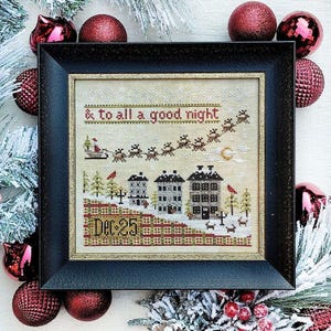 May include: A cross-stitch pattern of a winter scene with houses, a sleigh, and the text '& to all a good night'. The pattern is framed in a black frame and surrounded by red and green ornaments.