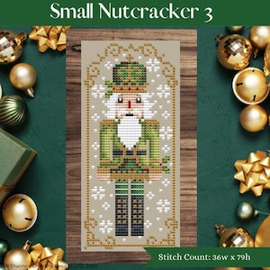 May include: A cross-stitch pattern featuring a detailed nutcracker design. The nutcracker wears a green uniform and a tall hat, with a white beard and a red face. The text "Small Nutcracker 3" is at the top. The stitch count is 36w x 79h.