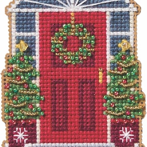 May include: A cross-stitch ornament featuring a red front door with a beaded wreath, flanked by two potted Christmas trees decorated with beads. The scene includes a blue arched window frame above the door and a gray step at the base.