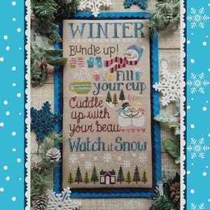 May include: A cross-stitch design with the word "WINTER" at the top, surrounded by winter-themed phrases and images. The design includes a snowman, snowflakes, and a cozy cabin, all set against a neutral background with a blue border.