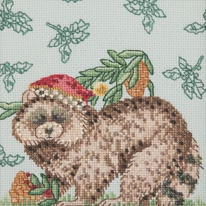 May include: Cross-stitch design of a bear wearing a red and white hat, holding a branch with orange fruit. The bear has brown and tan fur, with a light blue background featuring green floral patterns. A charming, handcrafted piece.