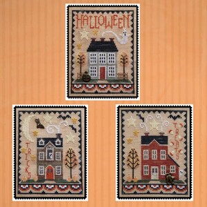 May include: Three framed cross-stitch samplers with Halloween themes. Each features a house, trees, and decorative elements. The top sampler reads "HALLOWEEN" with a ghost. The other two samplers have "TRICKS" and "TREATS" text.