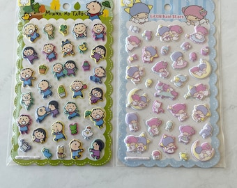 May include: Two packs of colourful stickers featuring cartoon characters. The pack on the left has a green border and features characters from the show "Minna no Tabo". The pack on the right has a blue border and features characters from the show "Little Twin Stars".