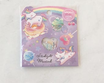May include: A pack of stickers featuring whimsical illustrations. The stickers include a unicorn, a rainbow, a donut, and other cute designs. The text "Starlight Musical" is written on the packaging. The stickers are in a clear plastic sleeve.