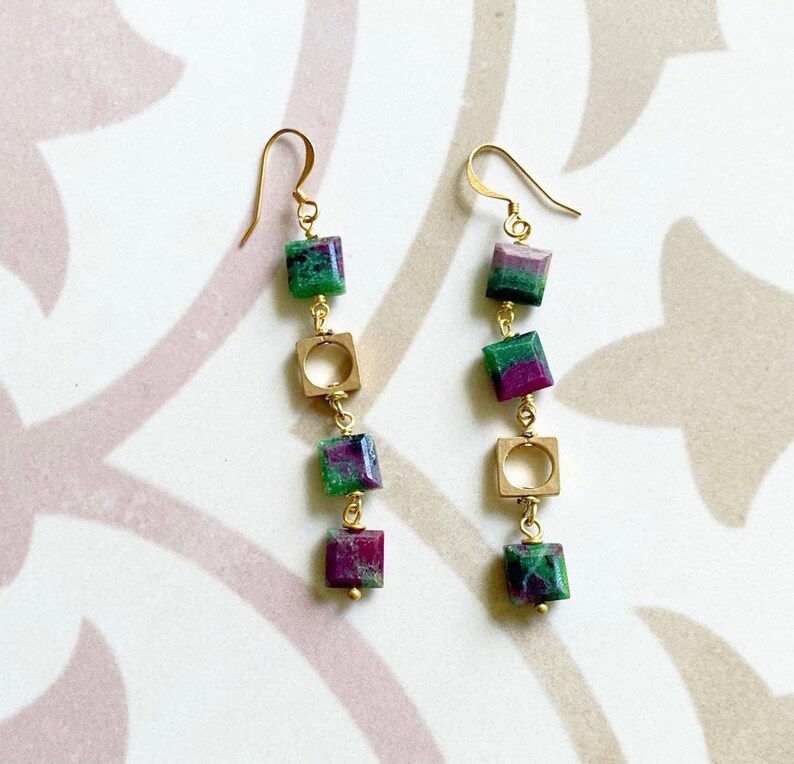 May include: Gold earrings with green and purple gemstone squares and gold hoops.