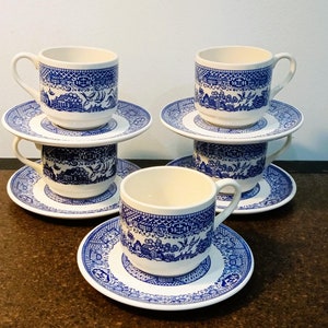 May include: Set of four blue and white teacups and saucers with a traditional Chinese pattern. The cups and saucers are made of ceramic and have a glossy finish.