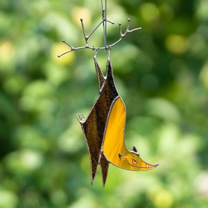 Stained Glass Hallowen Bat with orange body and brown wings decorated which is hanging on a copper wire
