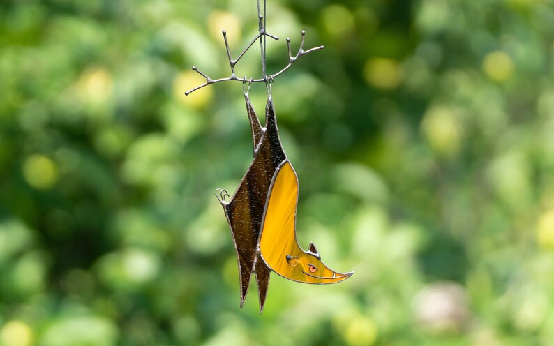 Stained Glass Hallowen Bat with orange body and brown wings decorated which is hanging on a copper wire