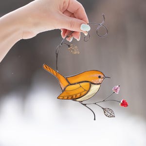 Carolina Wren stained glass suncatcher held in hand against soft blurred background, handmade bird decor for spring window display.