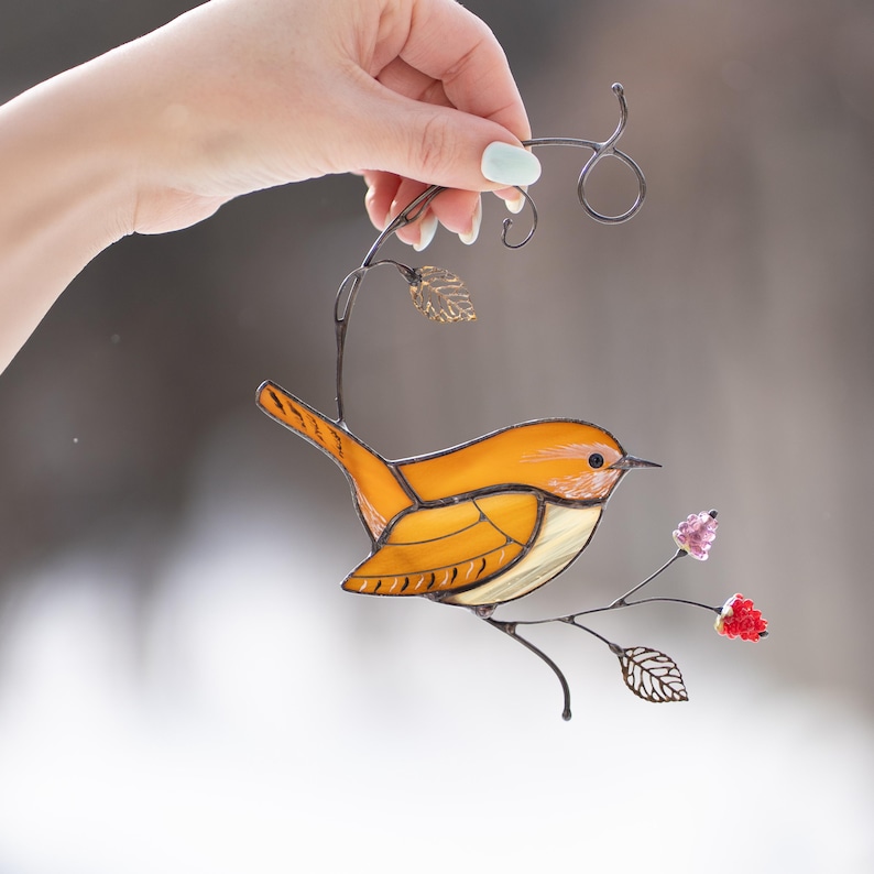 Carolina Wren stained glass suncatcher held in hand against soft blurred background, handmade bird decor for spring window display.