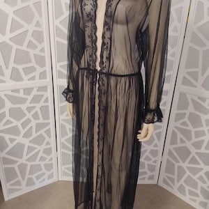 May include: A sheer black robe with long sleeves and delicate lace trim. The robe has a tie at the waist and lace detailing on the cuffs and along the open front. The garment is displayed on a mannequin.