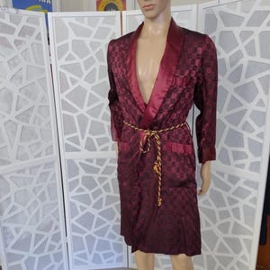 May include: A burgundy robe with a gold rope belt and a satin collar. The robe has a checkered pattern.