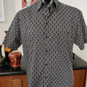 May include: A black and white short-sleeved button-down shirt with a geometric pattern of squares.