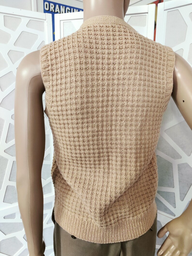May include: A beige knitted sleeveless vest with a waffle texture.