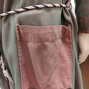 May include: A green and pink striped robe with a rope belt and a large pink pocket on the front.