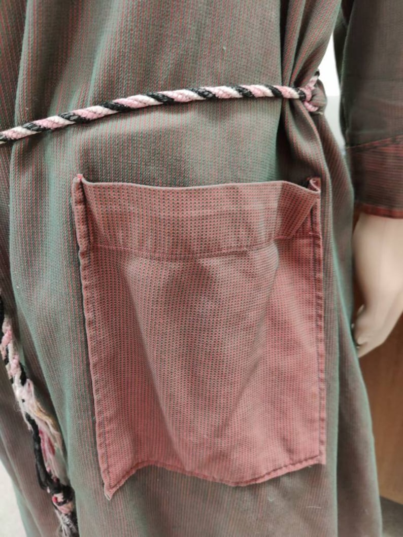 May include: A green and pink striped robe with a rope belt and a large pink pocket on the front.