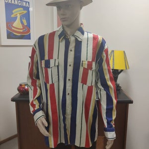 May include: A long-sleeved button-down shirt with vertical stripes in red, blue, yellow, and white. The shirt has two chest pockets and a button-up collar.