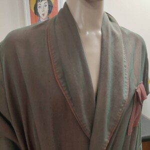 May include: A green and pink silk robe with a shawl collar and a tie at the waist. The robe has a pink satin trim.