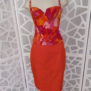 May include: A red and pink patterned top with a sweetheart neckline and thin straps, paired with a solid red skirt.