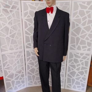 May include: A black double-breasted suit jacket with a white shirt and a red bow tie.