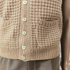May include: A brown knitted vest with a button-up front and two pockets. The vest has a waffle-like texture.