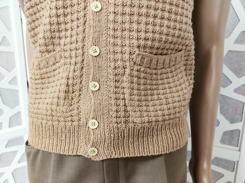 May include: A brown knitted vest with a button-up front and two pockets. The vest has a waffle-like texture.