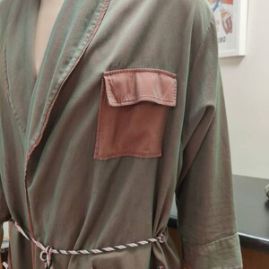 May include: A green and pink robe with a long sleeve and a tie belt. The robe has two pockets on the front.