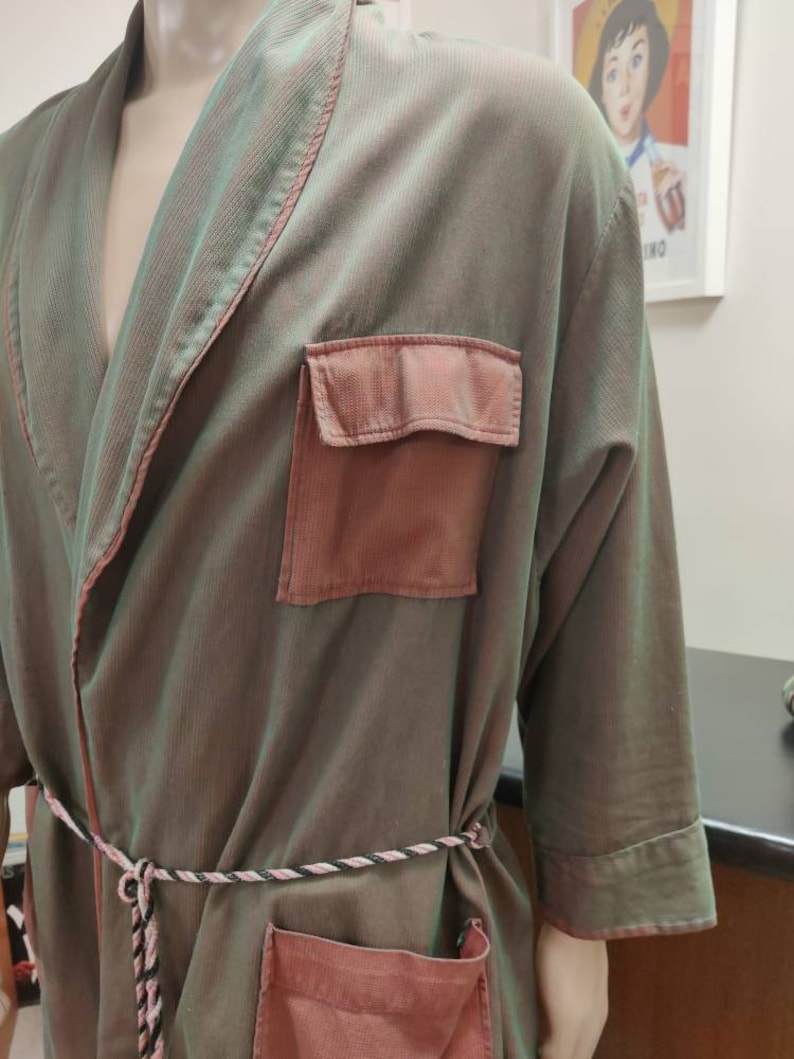 May include: A green and pink robe with a long sleeve and a tie belt. The robe has two pockets on the front.