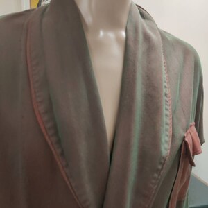 May include: A brown and green robe with a pink trim and a pink bow on the pocket.