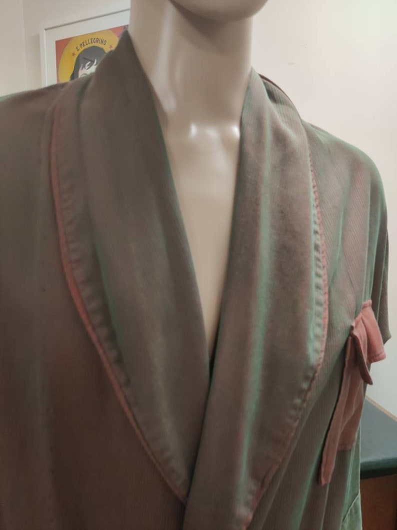 May include: A brown and green robe with a pink trim and a pink bow on the pocket.