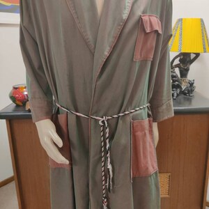 May include: A long, green and pink robe with a braided belt and two patch pockets. The robe is made of a soft, silky fabric.