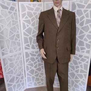 以下が含まれることがあります： 3つボタンのブラウンのピンストライプスーツ。スーツジャケットはノッチドラペルで、パンツはストレートレッグです。