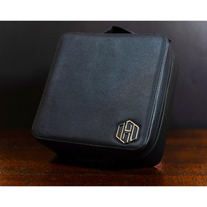 May include: Black leather travel case with a gold monogrammed logo.