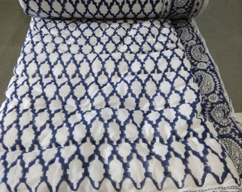 Könnte beinhalten: Eine weiße Baumwolldecke mit einem blauen geometrischen Muster und einem Paisley-Rand. Die Decke ist in der Mitte gefaltet und der Rand ist auf beiden Seiten sichtbar.