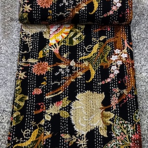 May include: Black kantha quilt with a floral pattern featuring brown branches, green leaves, and pink and yellow flowers. The quilt is hand-stitched with white thread.