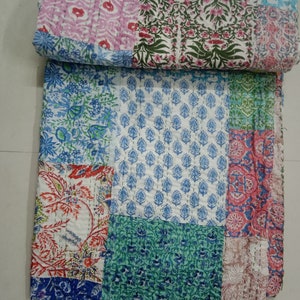May include: A patchwork quilt featuring a range of floral designs in shades of pink, blue, green, and red. The quilt is made from cotton and is hand-stitched.