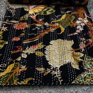 May include: Black kantha quilt with a floral pattern in shades of green, yellow, pink, and brown. The quilt is hand-stitched with white thread.
