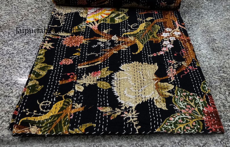 May include: Black kantha quilt with a floral pattern in shades of green, yellow, pink, and brown. The quilt is hand-stitched with white thread.