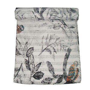 May include: A white kantha quilt with a black and gray floral pattern. The quilt is rolled up at the top and has a decorative stitch pattern.