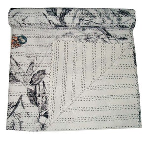May include: White kantha quilt with a black and gray floral pattern and black stitching. The quilt is folded in half and the stitching is visible on both sides.