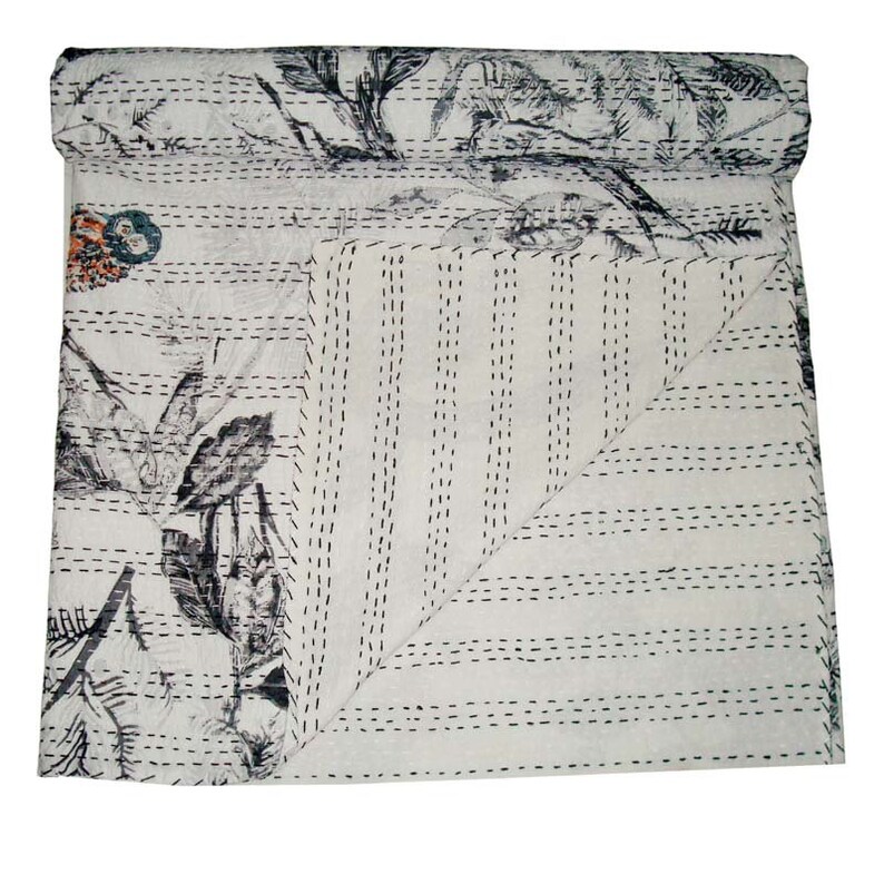 May include: White kantha quilt with a black and gray floral pattern and black stitching. The quilt is folded in half and the stitching is visible on both sides.