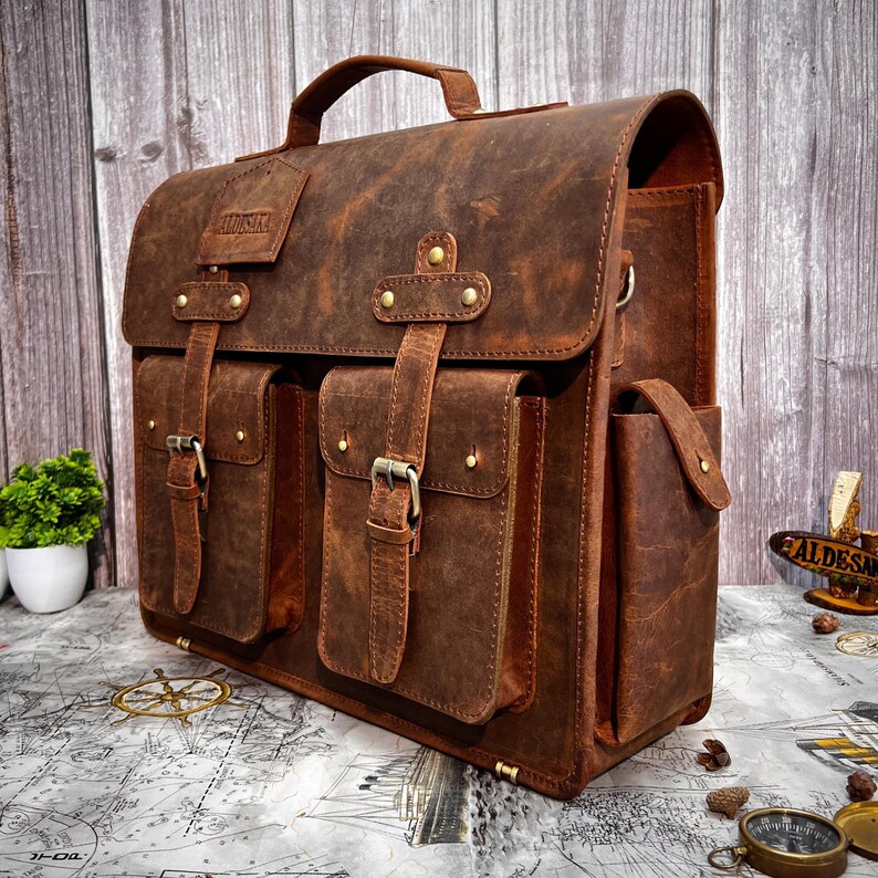 Angled back-right view of the leather satchel with reinforced stitching and metal hardware