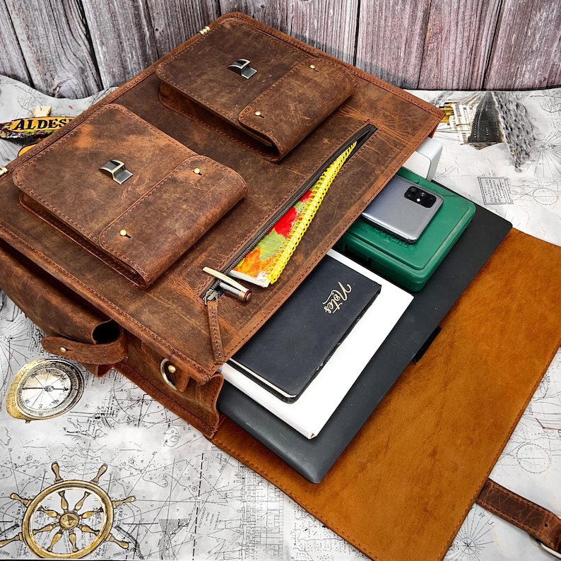 Top-down interior view of leather bag filled with laptop, books, and accessories