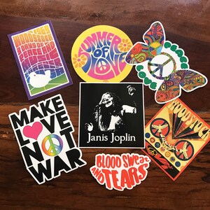 May include: A collection of seven vintage-style stickers with a 1960s theme. The stickers feature peace signs, butterflies, doves, and text that reads "Woodstock 3 Days of Peace and Music", "Summer of Love", "Make Love Not War", "Janis Joplin", "Blood Sweat and Tears", and "Woodstock".