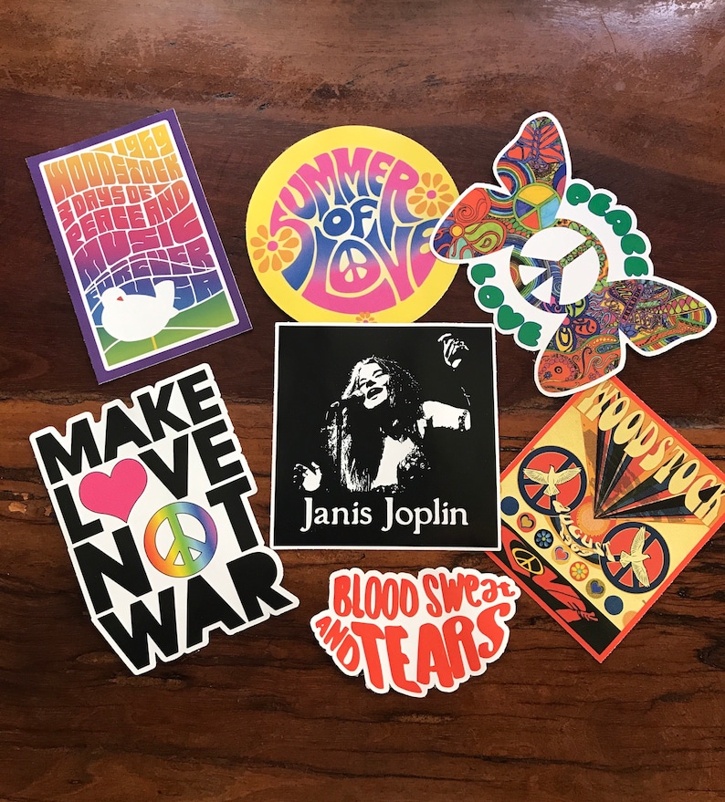 May include: A collection of seven vintage-style stickers with a 1960s theme. The stickers feature peace signs, butterflies, doves, and text that reads "Woodstock 3 Days of Peace and Music", "Summer of Love", "Make Love Not War", "Janis Joplin", "Blood Sweat and Tears", and "Woodstock".
