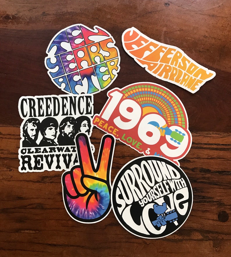May include: A set of six vintage-style stickers featuring psychedelic designs and text. The stickers include the words "Ten Years After", "Jefferson Airplane", "Creedence Clearwater Revival", "1969 Peace, Love, &", "Surround Yourself With Love", and a peace sign with a tie-dye pattern.