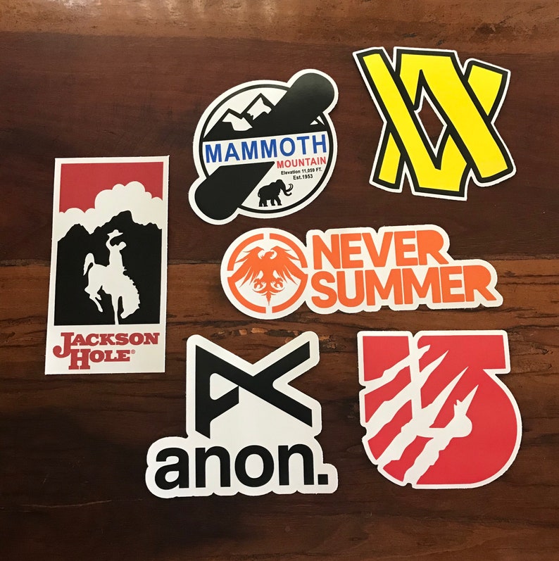 Puede incluir: Una colecci&oacute;n de nueve pegatinas coloridas con varios logotipos y dise&ntilde;os. Las pegatinas incluyen logotipos para Mammoth Mountain, Jackson Hole, Anon, Never Summer y algunas otras marcas. Las pegatinas est&aacute;n todas sobre una superficie de madera.