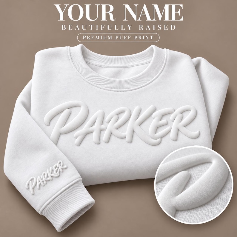 以下が含まれることがあります： 胸元と袖口に白い立体的なパフプリントで「PARKER」と書かれた白いクルーネックのスウェットシャツ。スウェットシャツの上部には「YOUR NAME BEAUTIFULLY RAISED PREMIUM PUFF PRINT」というテキストと円形の詳細画像が表示されています。
