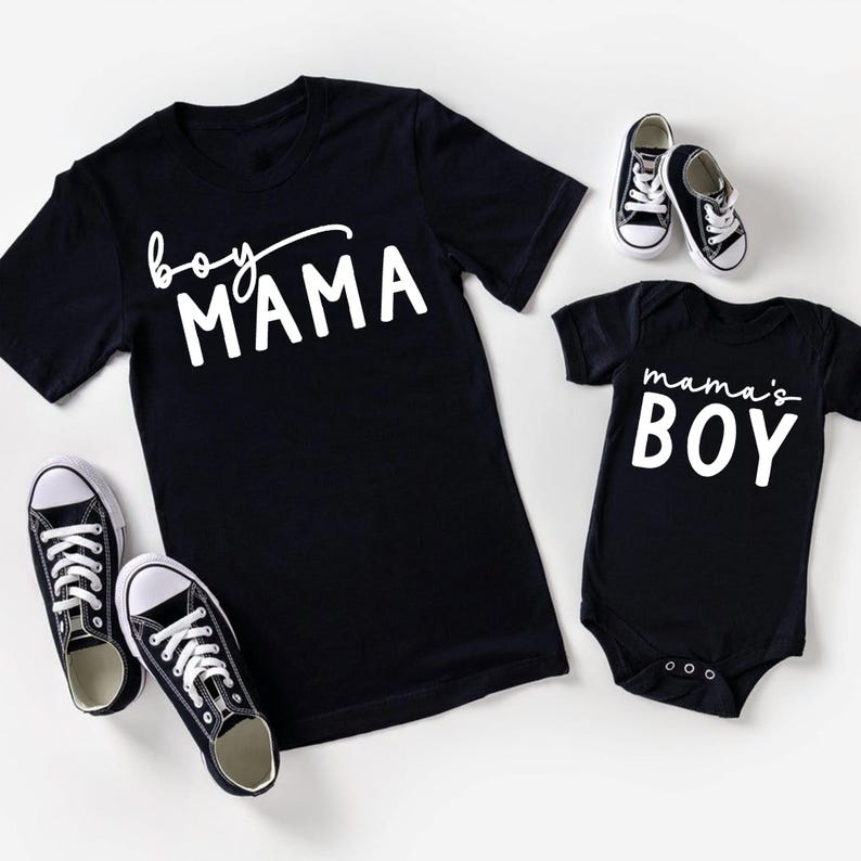 May include: Black t-shirts and a baby onesie with white text that reads "boy MAMA" and "mama's BOY". Two pairs of black and white sneakers are also in the image. The items are likely for a mother and son.